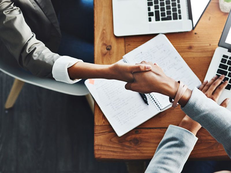 High angle shot of two businesswomen shaking hands in an office